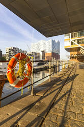 Germany, Hamburg, Life belt hanging on canal railing in Am Sandtorkai with Elbphilharmonie in background - IHF00501