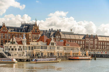 Historische Backsteingebäude am Flussufer mit vertäuten Booten in der Altstadt von Amsterdam - ADSF30731