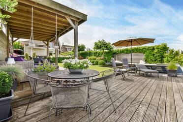 Flowers in pot on table among armchairs against lounger under parasol in patio of Utrecht Holland - ADSF30744