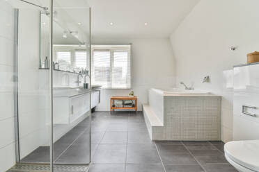 Contemporary bathroom interior with shower room against bathtub and window in house with tiled floor - ADSF30748
