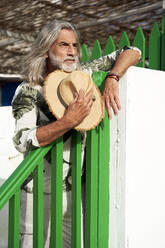 Bearded man with sun hat leaning on railing - VEGF05068