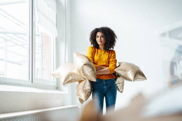 Afro woman holding foil balloons in living room - KNSF09058