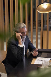 Male business person talking on mobile phone at hotel - VEGF05085