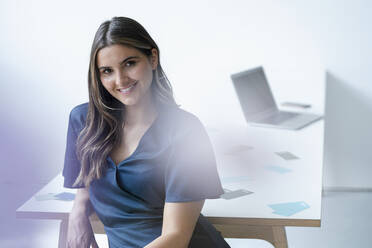 Young businesswoman leaning on office desk - KNSF09102