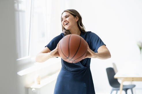 Glückliche Geschäftsfrau mit Basketball im Büro - KNSF09183