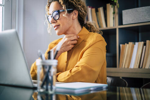 Lächelnde Geschäftsfrau mit Brille bei der Arbeit im Heimbüro - SIPF02484
