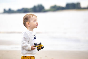 Niedlicher Junge mit Spielzeugauto am Strand - IHF00512