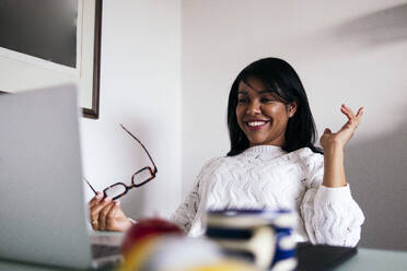 Female professional gesturing during video conference at home office - ASGF01582