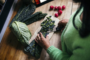 Woman cutting kale in kitchen - ASGF01606