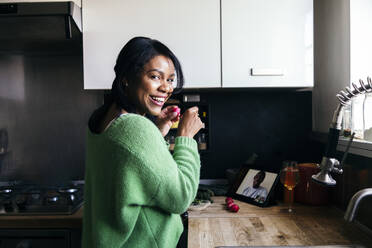Glückliche Frau hält Rettich während eines Videoanrufs über ein digitales Tablet zu Hause - ASGF01607