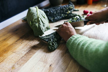 Mittlere erwachsene Frau schneidet Gemüse am Küchentisch - ASGF01612