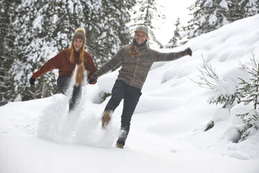 Playful couple kicking snow during winter - HHF05705