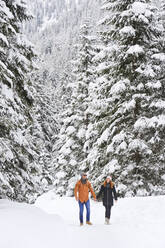 Mann und Frau halten sich beim Gehen im Schnee an den Händen - HHF05722