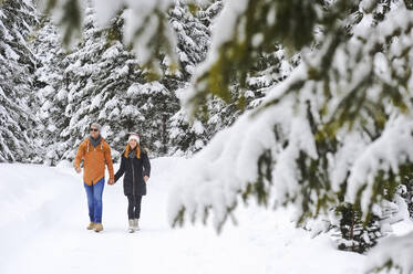 Man and woman enjoying leisure time while walking on snow during winter - HHF05723