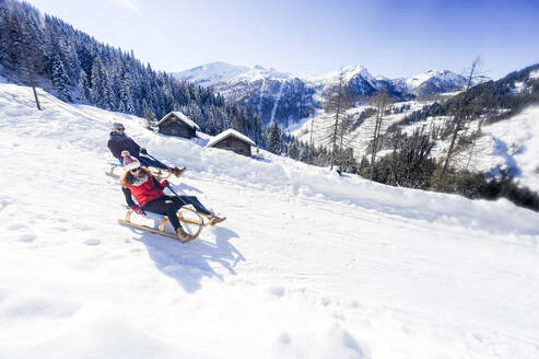 Playful couple sledding on snow during winter - HHF05732