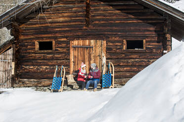 Ehepaar genießt ein Getränk in der Nähe einer Hütte im Winter - HHF05740