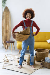 Afro-Frau mit Weidenkörben im Wohnzimmer stehend - GIOF13664