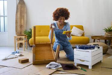 Rothaarige Afro-Frau mit altem Stuhl, die ein Smartphone zu Hause benutzt - GIOF13688