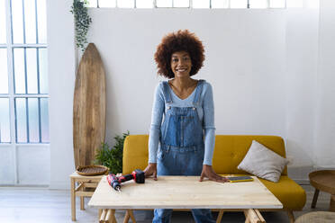 Rothaarige Afro-Frau steht am Tisch im Wohnzimmer - GIOF13706