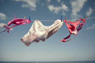 Bikinis auf der Wäscheleine an einem sonnigen Tag - AJOF01657