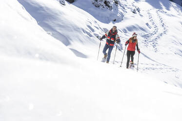 Man and woman snowshoeing while hiking on snow - HHF05764