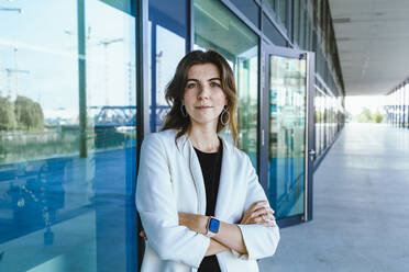 Female professional standing with arms crossed at building - IHF00556