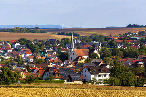 Ländliches Dorf im Herbst mit Kirche und Haus mit Solarzellen in der Mitte - NDF01352