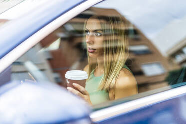 Woman holding coffee cup while driving car - DLTSF02215