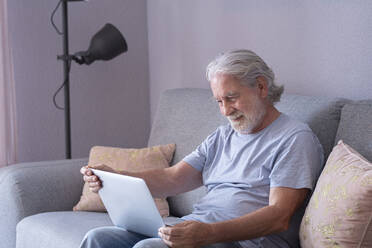 Senior man using laptop while sitting on sofa - SIPF02521