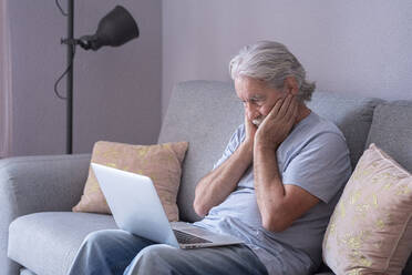 Man with head in head sitting on sofa at home - SIPF02522