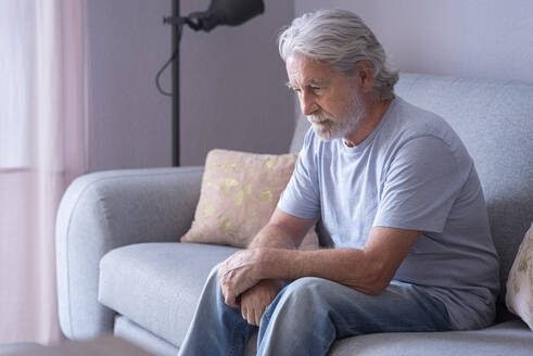Einsamer älterer Mann sitzt zu Hause auf dem Sofa - SIPF02523