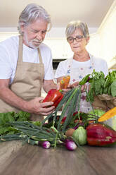 Älteres Paar prüft Gemüse auf dem Tisch zu Hause - SIPF02542