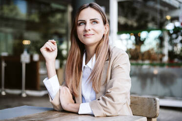 Smiling businesswoman sitting at cafe table - EBBF04722