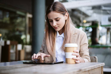 Weibliche Geschäftsfrau, die ein digitales Tablet am Kaffeetisch benutzt - EBBF04728