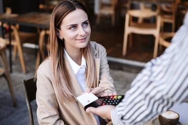 Geschäftsfrau beim kontaktlosen Bezahlen mit Kreditkarte in einem Cafe - EBBF04736