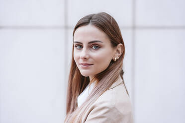 Young businesswoman with blond hair by white wall - EBBF04743