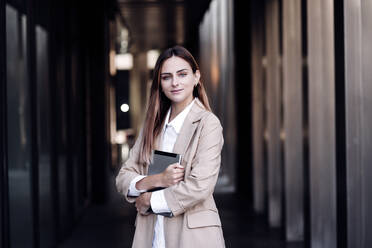 Female business professional holding digital tablet at corridor - EBBF04780