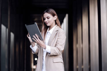 Young businesswoman using digital tablet at corridor - EBBF04781