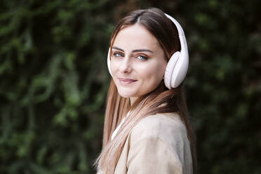 Schöne junge Geschäftsfrau mit blondem Haar hört Musik über drahtlose Kopfhörer - EBBF04807