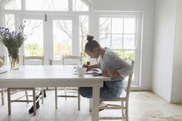 Teenage girl painting with watercolours in a light filled room - MINF16466