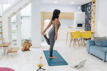 Ältere weibliche Influencerin macht Yoga und filmt dabei ihr Workout im Wohnzimmer mit dem Handy - JRVF01882