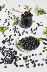 Raw blueberries and glass of homemade blueberry jam on white table - GWF07188
