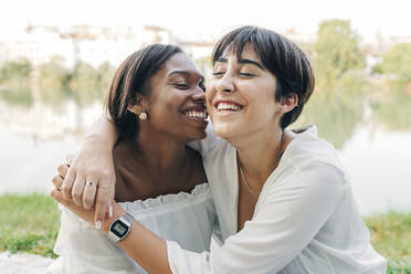 Cheerful women laughing at lakeshore - JRVF01912