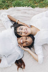 Happy girlfriends touching faces on blanket - JRVF01924