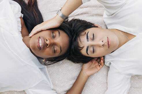 Freundinnen mit geschlossenen Augen auf einer Decke liegend - JRVF01929