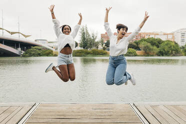 Carefree women jumping on pier - JRVF01931