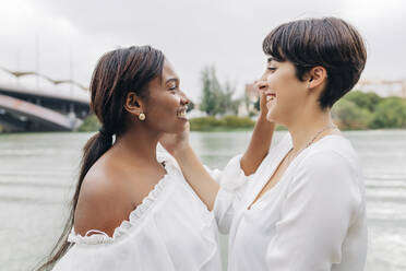 Lächelnde lesbische Frauen schauen sich am See an - JRVF01945