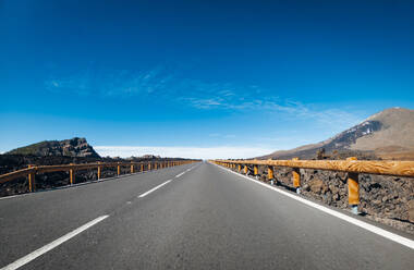 Aussicht auf eine leere Straße inmitten der Berge an einem sonnigen Tag - SIPF02571