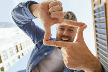 Happy man making rectangle shape with fingers - IHF00580