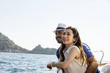 Happy couple standing together in motorboat during sunny day - EIF02102